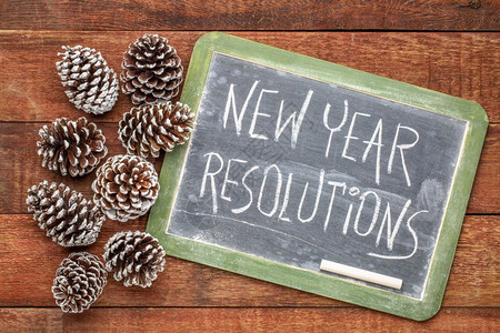 新年决议黑板上白粉笔迹与冻松锥子和生锈的谷仓木对立图片