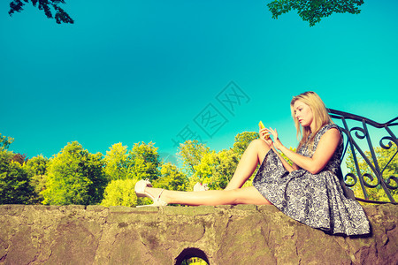 妇女坐在公园休息和使用手机在外闲暇时间妇女坐在公园休息和使用手机图片