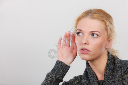 手势流言听力丧失或混乱妇女为更好的听力而亲手倾工作室在浅灰色后脑中拍摄图片