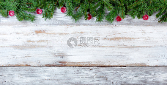 圣诞长绿树枝和白上红蜡烛的顶端边界图片