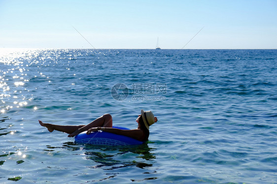 美丽的年轻女士带充气环放松在海上图片