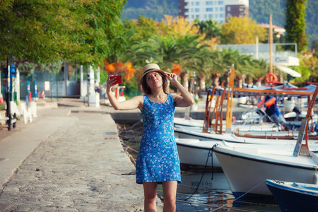 戴帽子的年轻女旅行者在夏季阳光明媚的地中海城市拍摄自带智能手机相的年轻女旅行者在暑假时拍摄自带智能手机相的年轻女旅行者在夏季拍摄图片