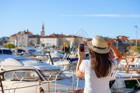 戴帽子的年轻女旅行者用智能手机相拍摄夏季阳光的布德瓦风景照片在黑山夏季地中海目的拍摄布诺特女孩照片戴帽子的年轻女旅行者用智能手机图片