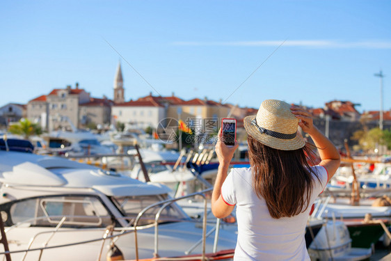 戴帽子的年轻女旅行者用智能手机相拍摄夏季阳光的布德瓦风景照片在黑山夏季地中海目的拍摄布诺特女孩照片戴帽子的年轻女旅行者用智能手机图片