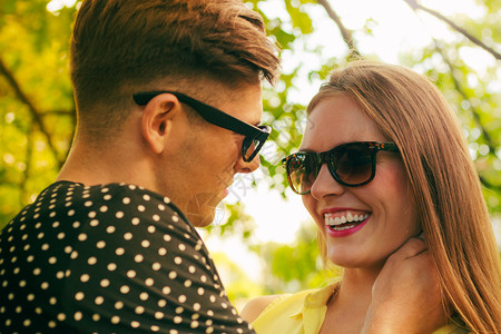 快乐的年轻情侣戴着太阳镜在公园散步图片