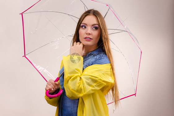 身着防水的黄大衣有透明伞式保护的女时装雨衣少气象学预报和天气季节概念身着防水大衣的妇女则身着雨伞式保护图片