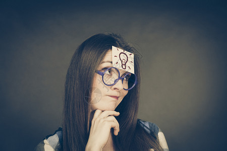 妇女困惑的思维寻求解决办法纸牌上盖着灯泡的学生女孩寻找新的想法Eureka创造力概念妇女思维寻求解决办法图片