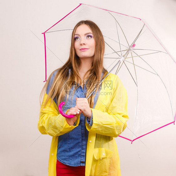 身着防水的黄大衣有透明伞式保护的女时装雨衣少气象学预报和天气季节概念身着防水大衣的妇女则身着雨伞式保护图片