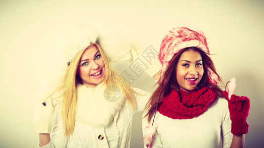 两个笑的金发女孩和穆拉托穿着温暖的红白衣服肖像穿着毛帽围巾手套的迷人女穿着温暖的冬装两个笑女孩图片