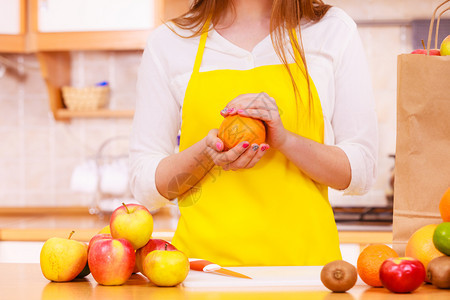 在厨房里吃很多水果年轻家庭主妇拿着橙子水果健康饮食烹饪素饮和人的概念图片