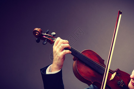 音乐激情爱好概念把穿着优雅小提琴的年轻人关起来把黑背景的摄影棚拍下来把穿着优雅小提琴的男子拍下来把穿着优雅小提琴的男子拉起来图片