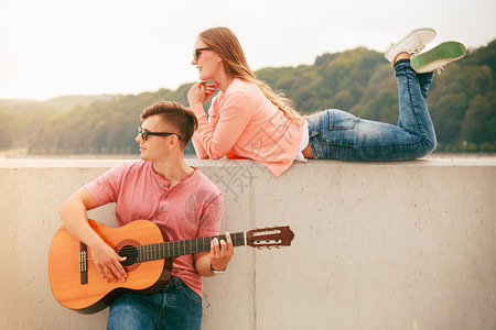 年轻情侣在海边弹吉他约会图片