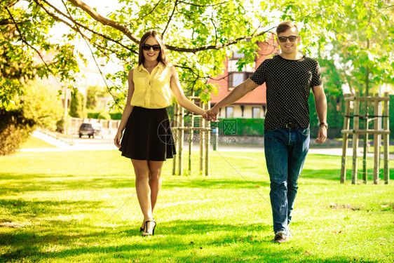 情侣在公园拉手年轻女孩和男一起散步夫妇在公园拉手图片