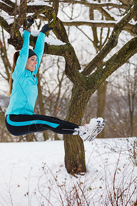 年轻女孩雪天挂在树上健身图片