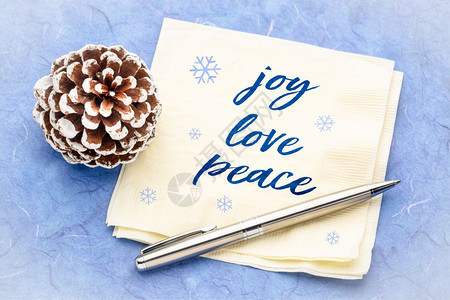 欢乐爱和平概念纸巾上的笔迹用松锥形装饰和蓝色木莓纸图片
