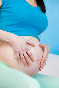 孕妇舒适地坐在家里沙发上抚摸肚子怀孕产和预期概念孕妇抚摸肚子图片