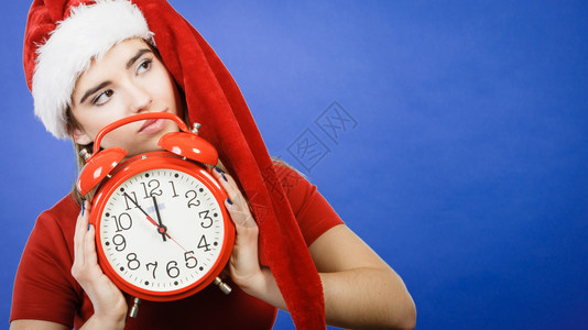 穿着圣诞老人帮手服装的妇女穿着圣诞老人的服装穿着红色大钟等庆祝背景图片