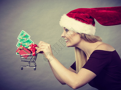 戴圣诞老人帮手帽子的快乐妇女拿着小面包车手持圣诞树和礼物在车内奔跑出售图片