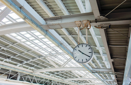火车站的乘客时钟在建筑背景中寻找金属结构屋顶的时间图片