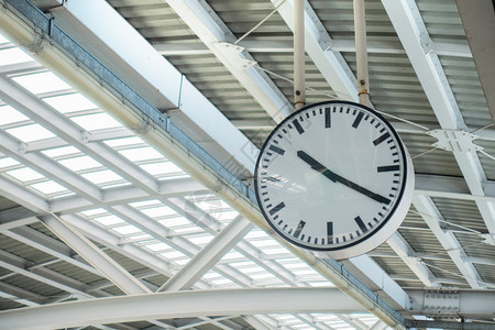 火车站的乘客时钟在建筑背景中寻找金属结构屋顶的时间图片