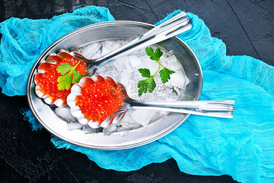 金属托盘上的勺中红鲑鱼子酱图片