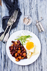 炸豆子和鸡蛋在早餐盘子上吃图片