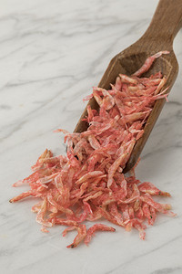 小干虾传统日本樱桃木勺上的小粉红虾干背景