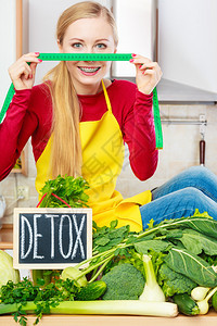 厨房的年轻女有很多绿色蔬菜配有脱毒标志的餐桌图片