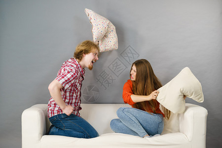 愤怒的情侣在沙发上用枕头打架图片
