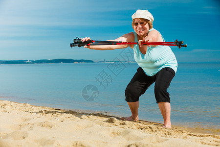 年长妇女享受挪威散步在海边和阳光明媚的夏日用电线杆进行热身锻炼健康老年活动图片