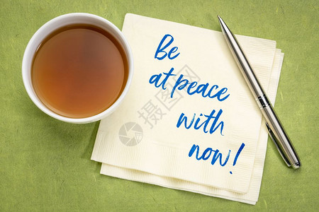 与现在和平相处鼓舞人心的笔迹在餐巾纸上加一杯茶图片