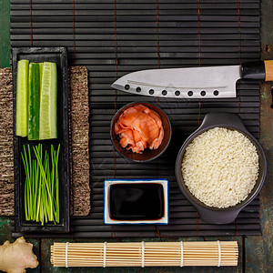 传统寿司成份大米鲑鱼肉姜黄瓜薯条酱油和深生背景的竹垫亚洲食物背景顶端视图平地传统寿司成份平地图片