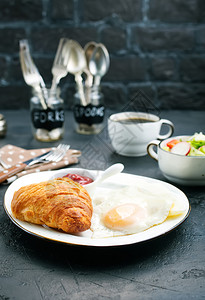 白色面包餐桌上的早炒鸡蛋和羊角面包背景
