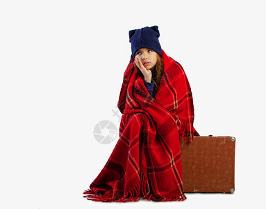 一个小女孩正等待着前往温暖的土地坐在装着行李的手提箱上但当她被寒冷的羊毛毯包在里时她却等待着前往温暖的土地旅行图片