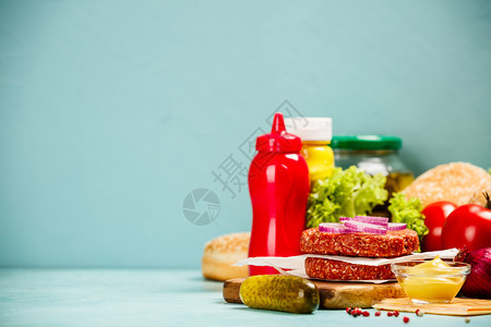 土制汉堡包生牛肉饼芝麻面包和蓝背景汉堡的其他成份制作汉堡包的成分文字空间图片
