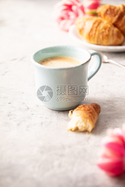 上午咖啡羊角面包和以浅灰底色背景的春郁金花早餐概念图片