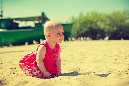 幼儿坐在海边滩上玩图片