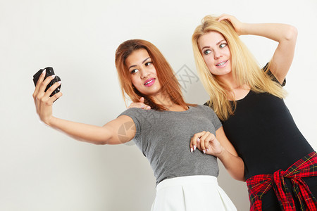 青年金发女子和混合种族用照相机拍自图片