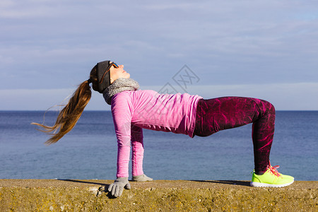 在寒冷的天气下在海边外穿着温暖运动服的女员培训在冬季或秋天的体育和活动图片