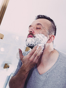 男人在修剪胡子前准备面部毛发应用剃须奶油泡沫糖男美容治疗概念男人在剪胡子前涂剃须膏图片