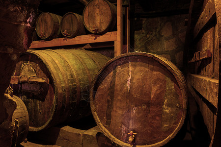 实木酒窖地窖中的旧木制葡萄酒桶背景