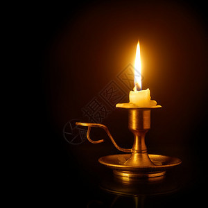 在黑背景的旧铜烛台上烧蜡背景图片
