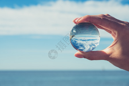 Women握着晶体球的手望向海洋和天空创意摄影晶体球折射图片
