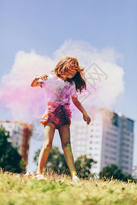 女孩在城市公园玩多彩的辣椒粉云中玩耍无忧虑的童年欢呼庆小女孩在多彩的辣椒粉云中玩耍图片