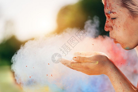 年轻女人用手吹彩色粉末霍利节图片