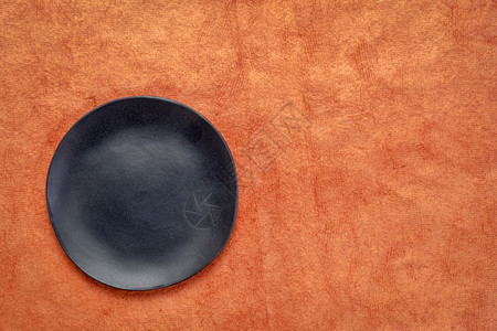 南瓜橙色手工制作的HuunMayan纸上不定期边缘的黑瓷板带有复制空间图片
