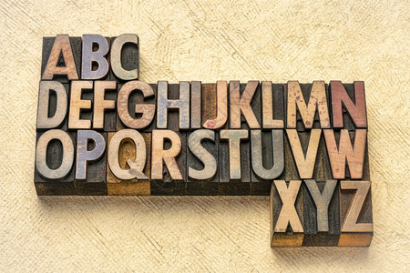 与纹理树皮纸相比的旧印刷木型打块中的抽象字母图片