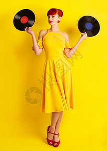 穿黄色裙子的女孩身穿黄色衣服着两张黑乙烯胶唱片背着明亮的景图片