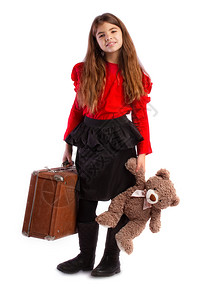 小女孩收拾了她的旧复式行李箱和她最喜欢的泰迪熊一起等图片