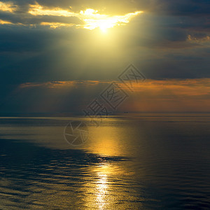 明亮的太阳在黑云中笼罩有太阳足迹的海洋上图片
